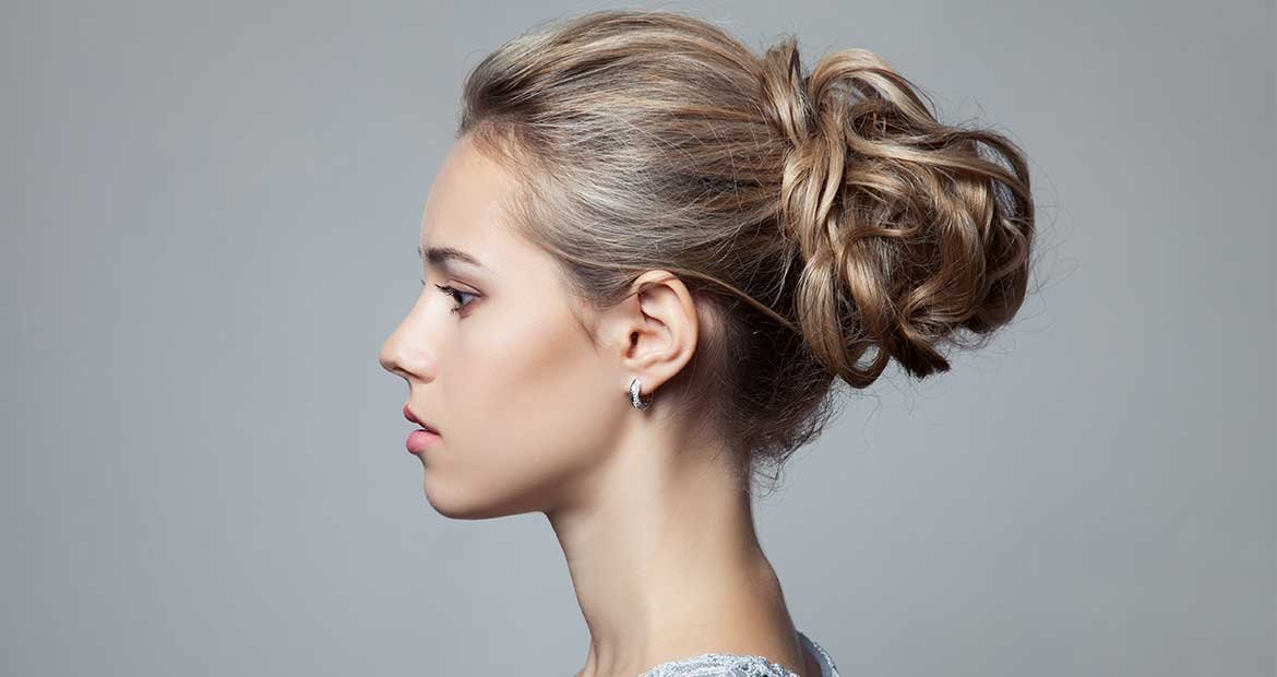 Modelo loira de lado com coque no cabelo
